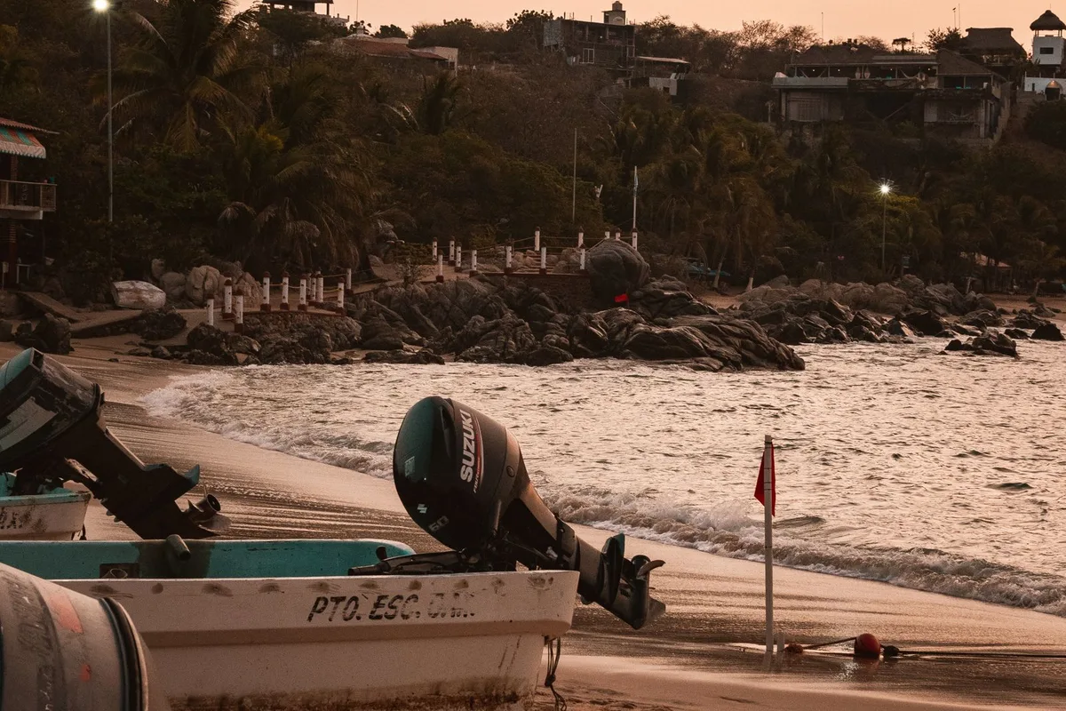 Fishing pangas pulled up on the sand at Puerto Angelito at dusk, outboard motors tilted