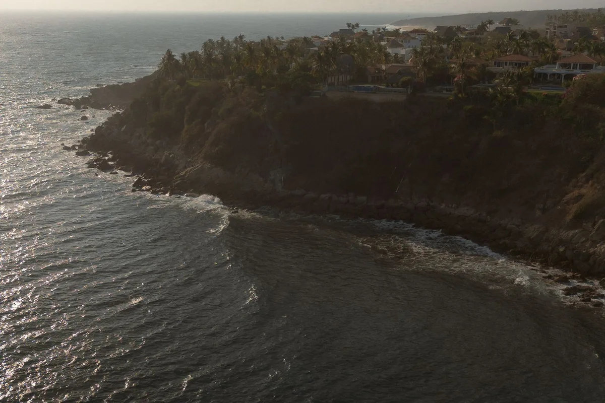 A green headland falling to a turquoise bay on the Oaxaca coast east of Puerto Escondido