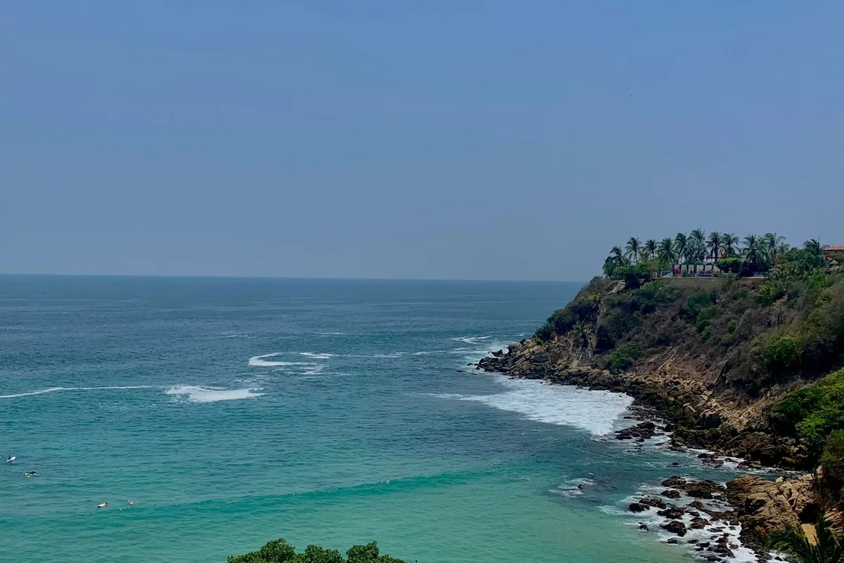 Playa Carrizalillo from the clifftop, a turquoise cove ringed by palapas below Rinconada