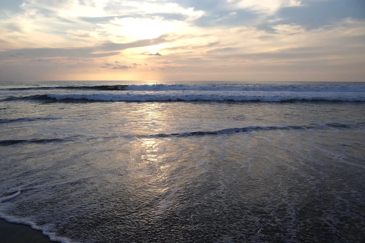 Surf rolling in at Zicatela under a low sun, the water lit copper