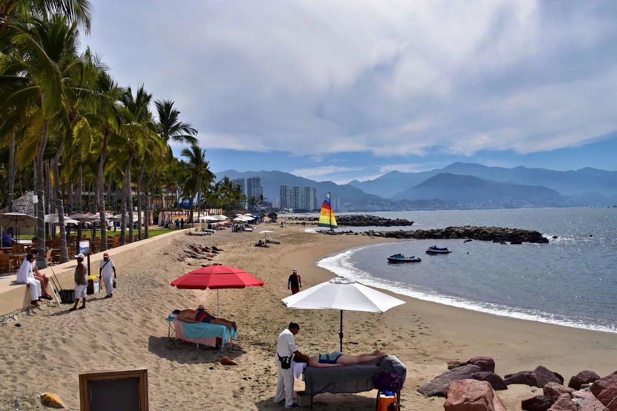 Playa de los Muertos under the palms, with the Los Muertos Pier sail and Banderas Bay beyond