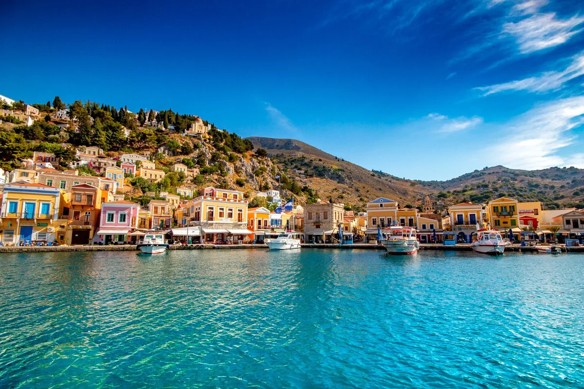The pastel harbour of Symi island, neoclassical houses rising around the bay