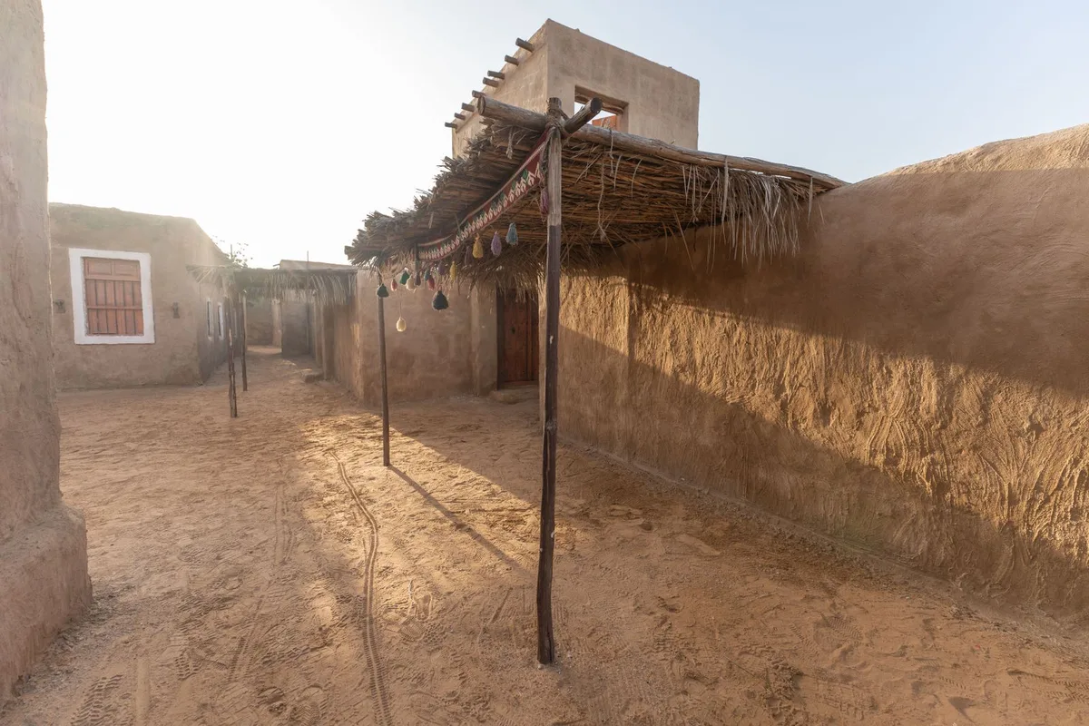 A historic mud-brick courtyard in Diriyah, palm-thatch shades over the Najdi walls