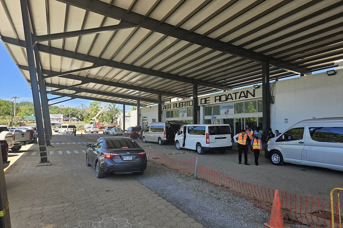 Taxis and minivans waiting under the canopy outside Roatan airport
