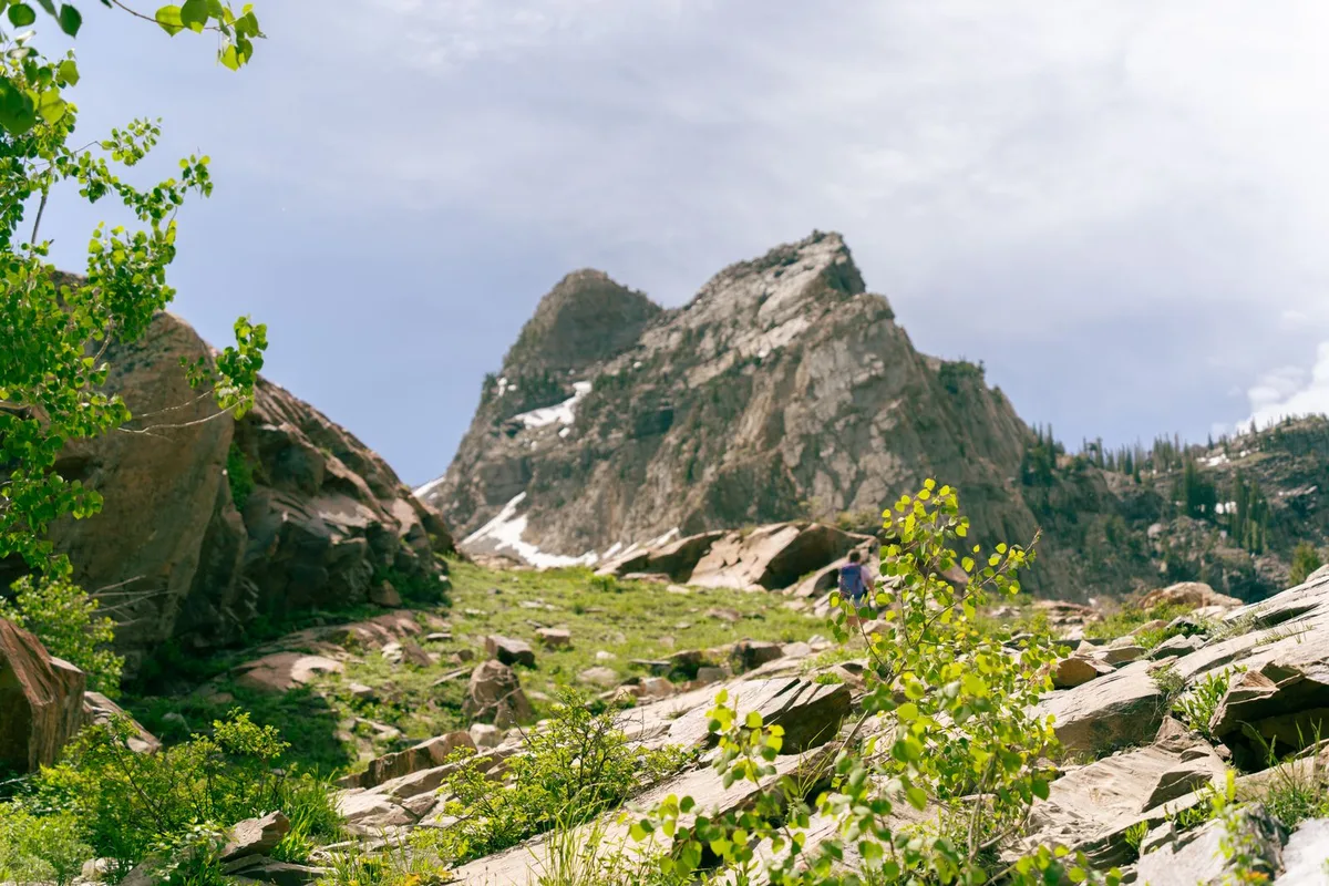 A hiker on a rocky trail below a Wasatch peak