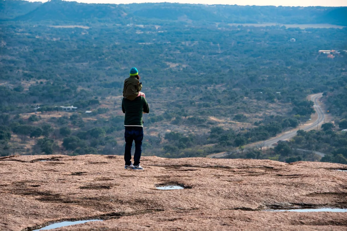 A hiker looking over the Texas Hill Country from a granite dome near Fredericksburg