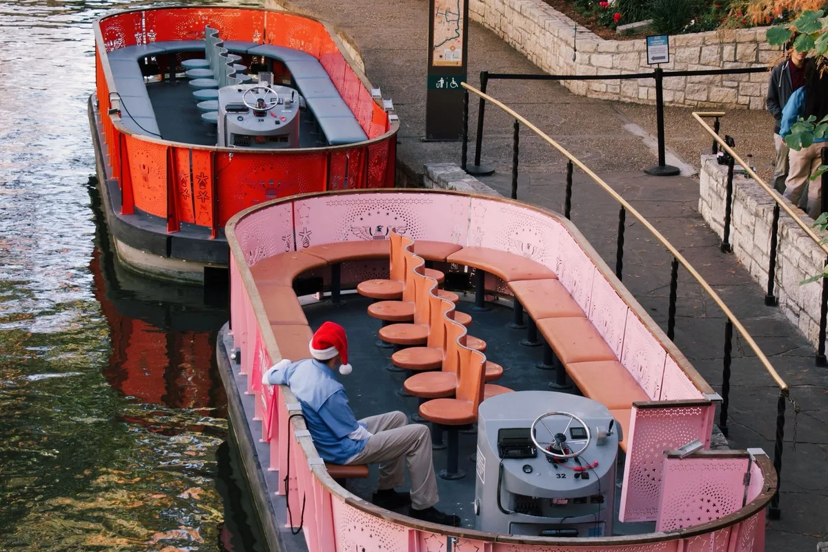 River Walk tour barges on the San Antonio River seen from a bridge above