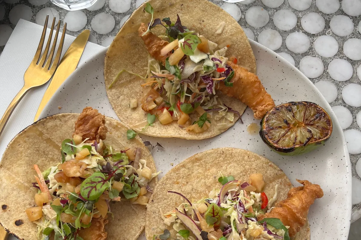 Baja fish and shrimp tacos on a plate with slaw and grilled lime