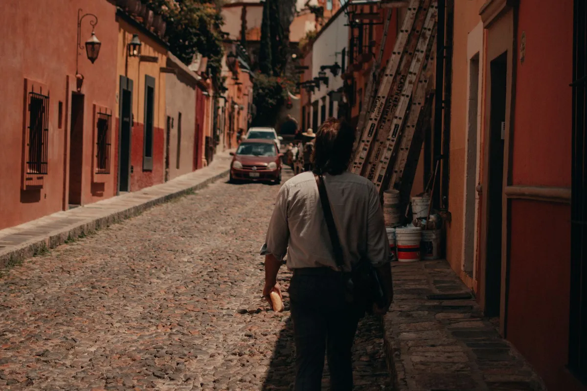 A walker on a cobbled street in San Miguel's centro, colourful housefronts either side
