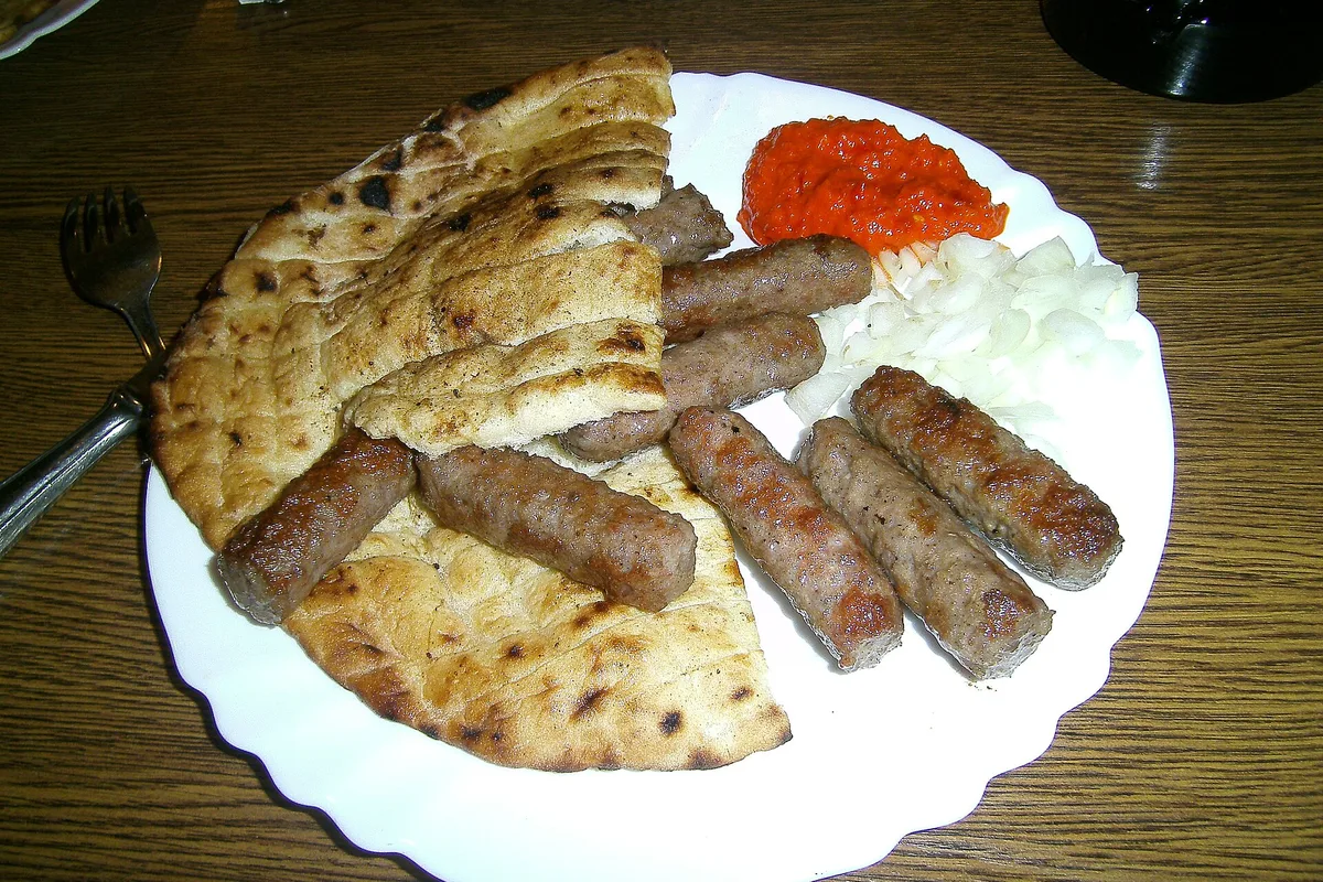 A plate of ćevapi with somun flatbread, chopped onion and ajvar in Bosnia
