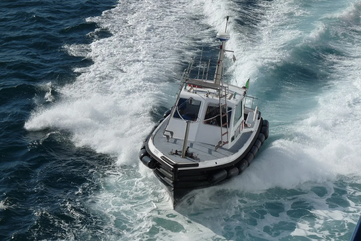 A boat powering through the water in Cagliari harbour, starting point for Gulf of Cagliari tours