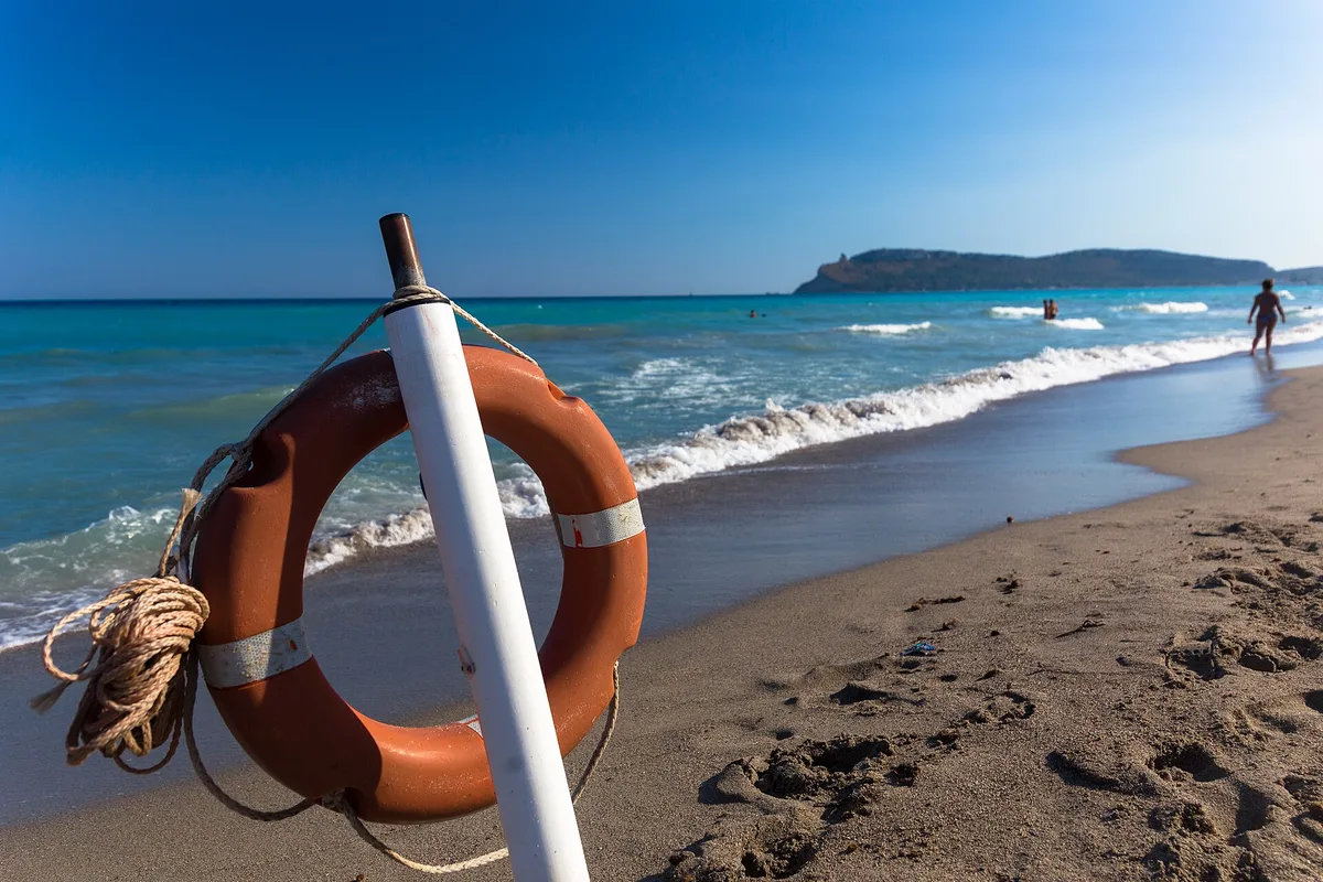 Poetto beach in Cagliari, a lifebuoy on the sand with the Sella del Diavolo headland across the bay
