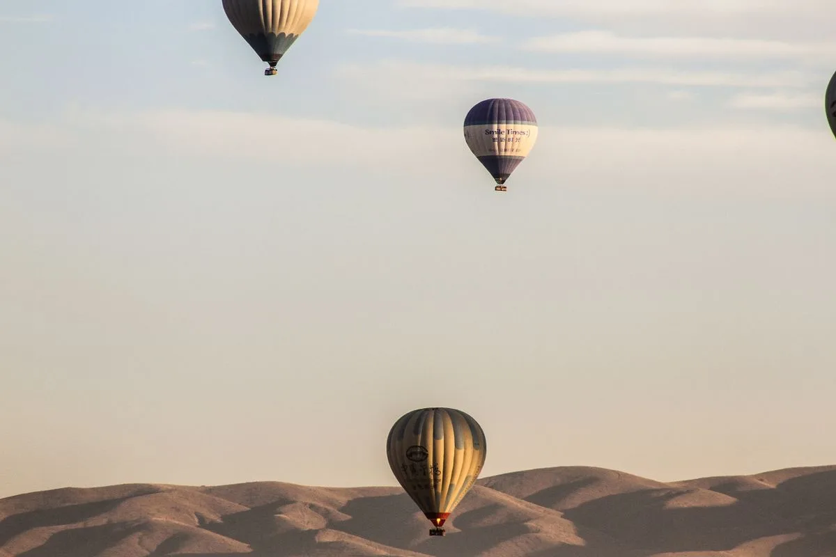 Hot air balloons drifting over the desert at dawn