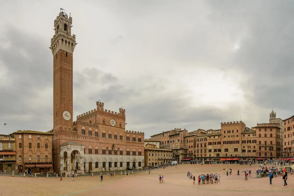 Piazza del Campo and the Torre del Mangia in Siena under a cloudy sky