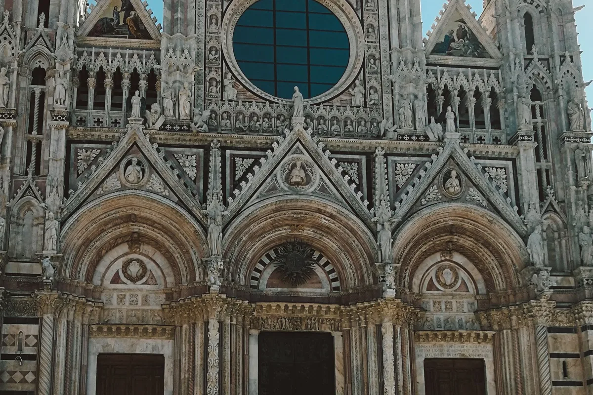 The striped marble facade of Siena Cathedral with its rose window and three portals