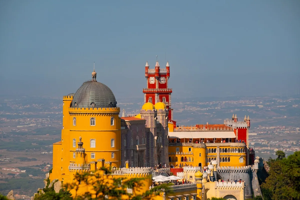 The Pena Palace above Sintra, its yellow walls and red clock tower against a hazy sky