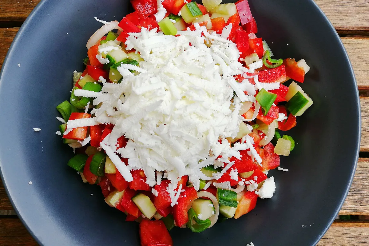 A shopska salad of chopped tomatoes, cucumber and peppers under grated sirene cheese