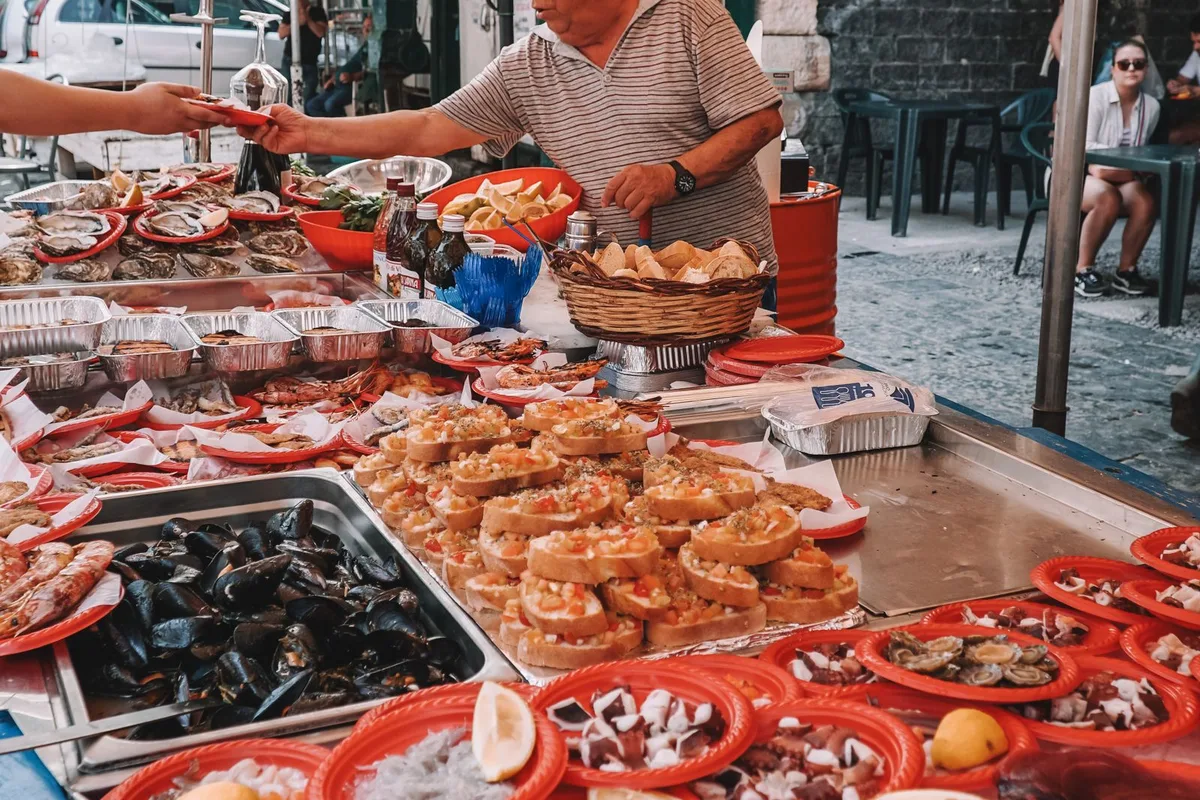 A seafood stall at a Sicilian market, red trays of shellfish and the morning catch