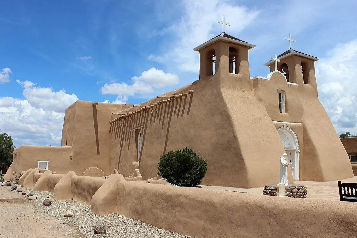 The adobe San Francisco de Asis Mission Church at Ranchos de Taos, its sculpted buttresses against a blue sky