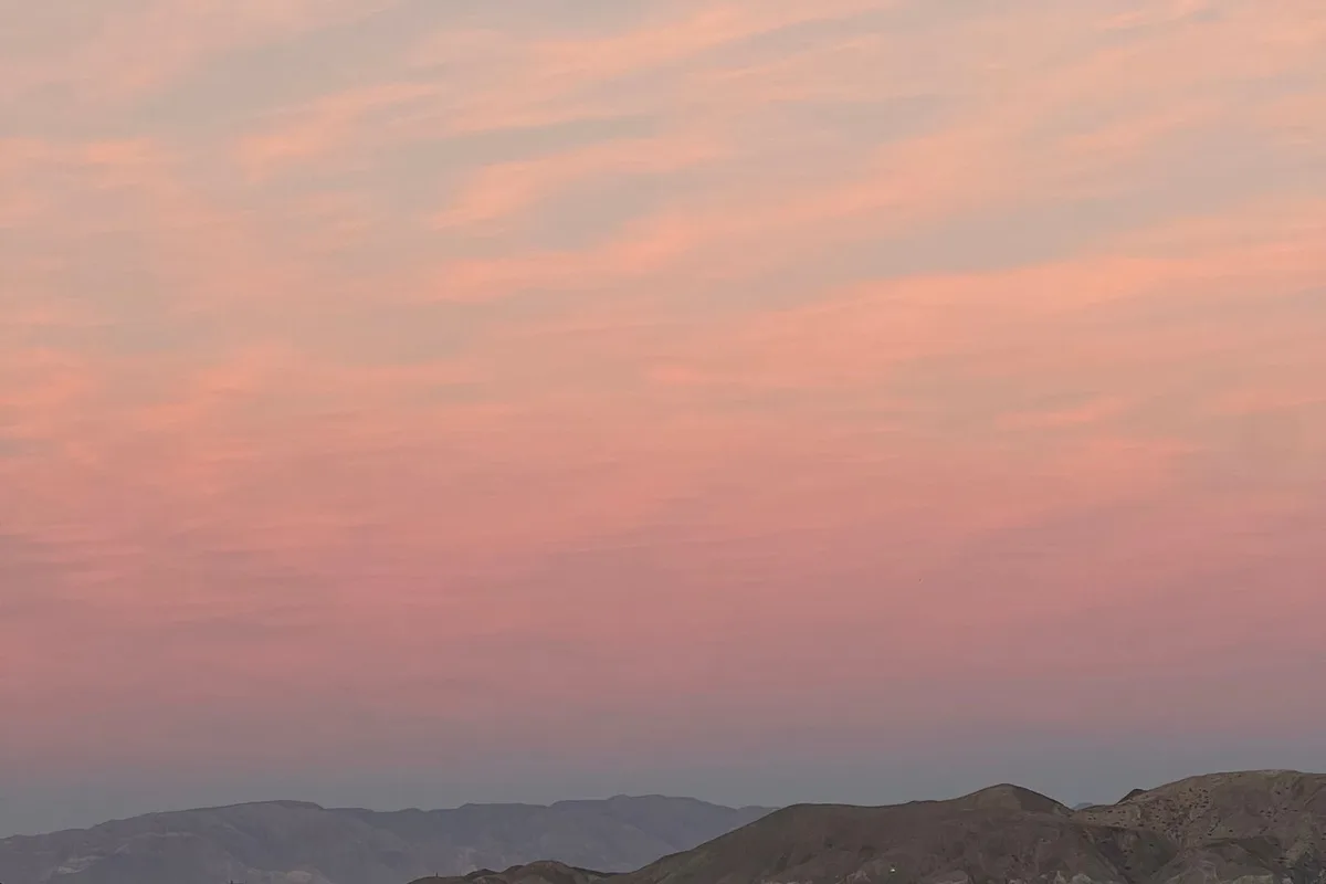 Pink sunset light over a calm Baja beach and distant headlands