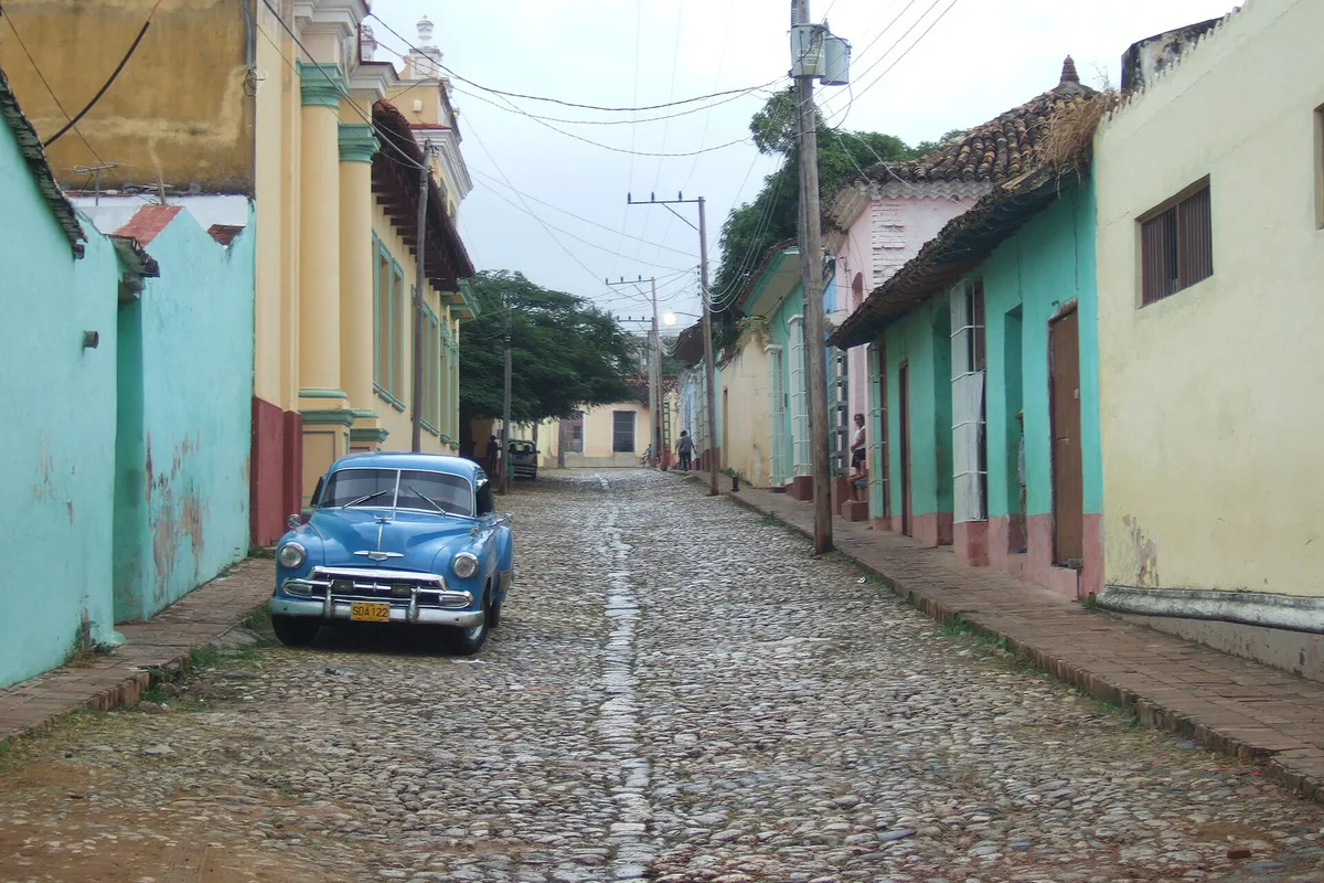 A cobbled Trinidad street, pastel houses and a 1950s almendrón