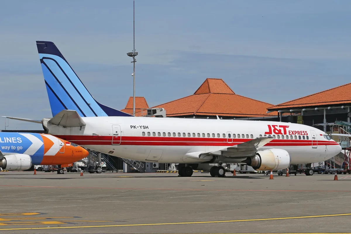 A jet on the apron in front of the Balinese-roofed terminal at Ngurah Rai Airport