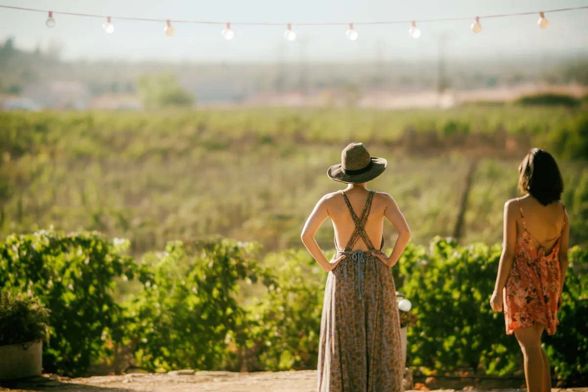 Two visitors looking over the El Mogor vineyard toward the valley hills at sunset