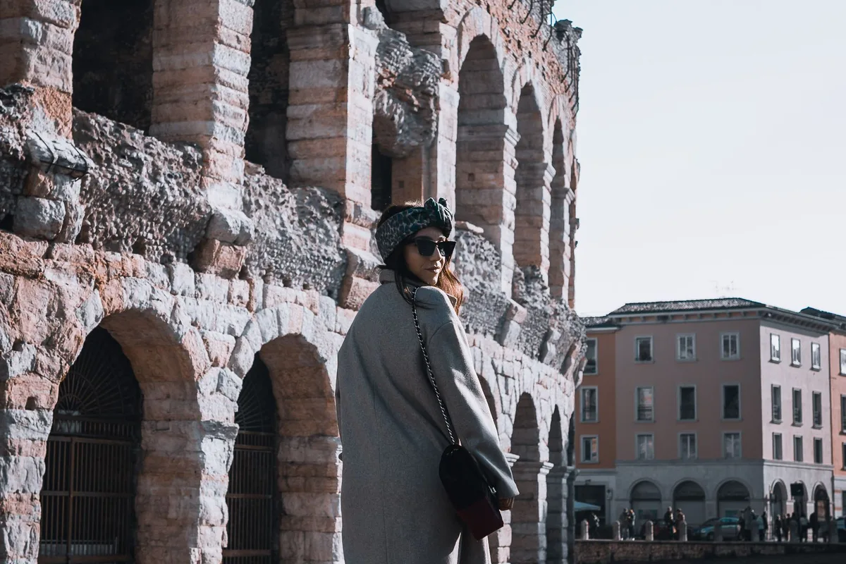 A visitor standing before the stone arches of the Verona Arena in Piazza Bra