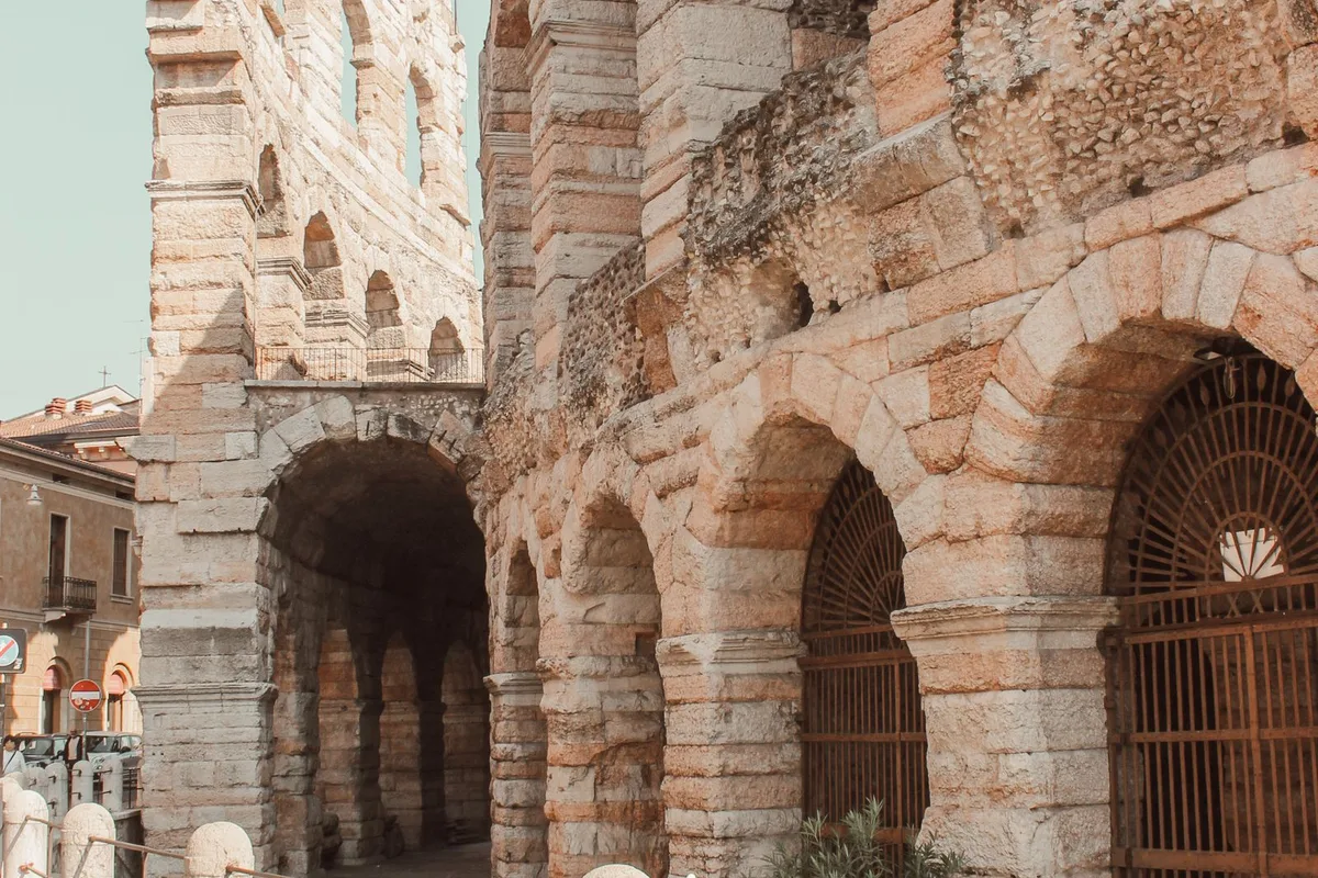 The pink stone arches of the Verona Arena, a bicycle leaning against the wall below