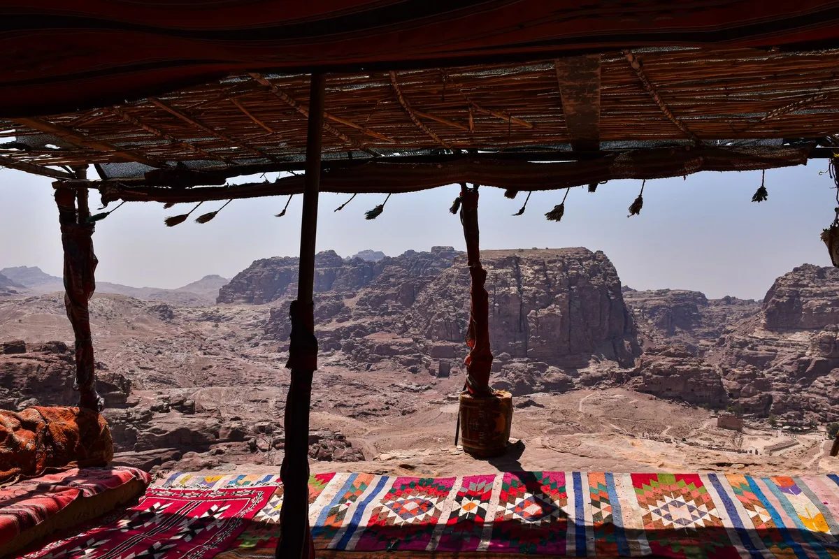 A Bedouin rest stop terrace with carpets and cushions above the desert valley