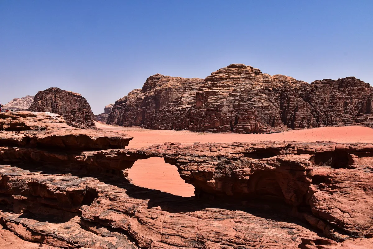 A natural rock bridge spanning the red sand in Wadi Rum