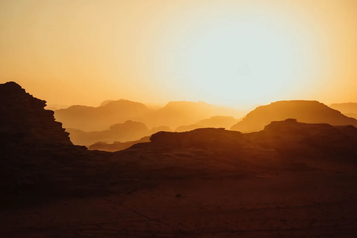 Golden sunrise light over the layered mountains of Wadi Rum