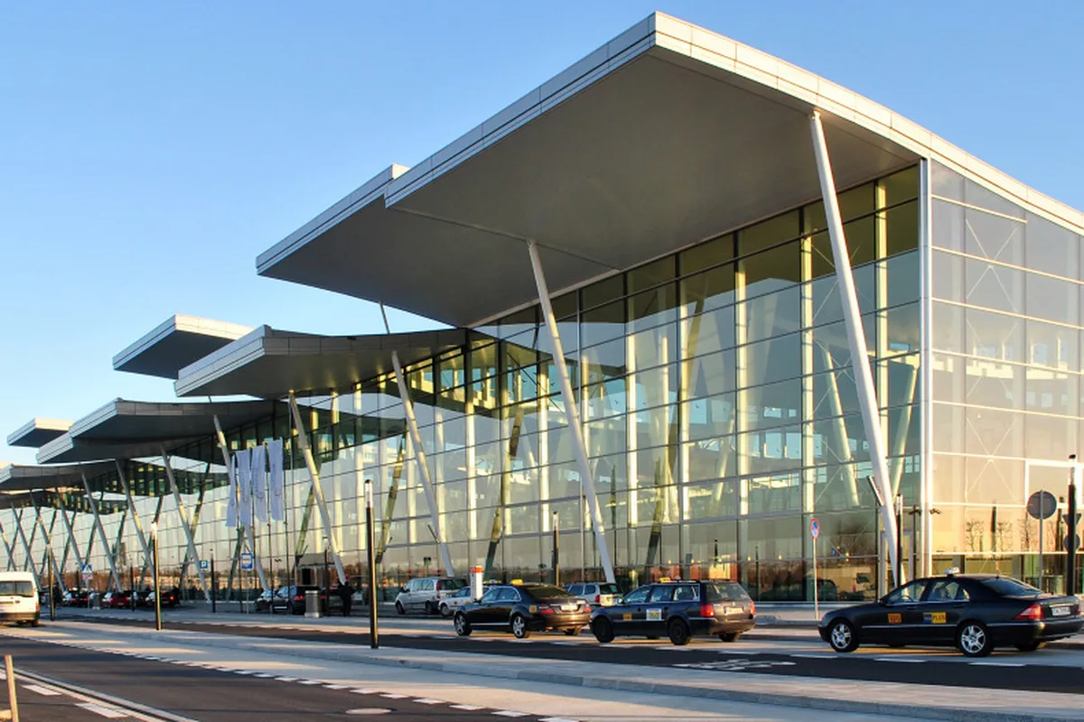 The glass terminal of Wrocław Copernicus Airport, taxis waiting at the kerb outside arrivals